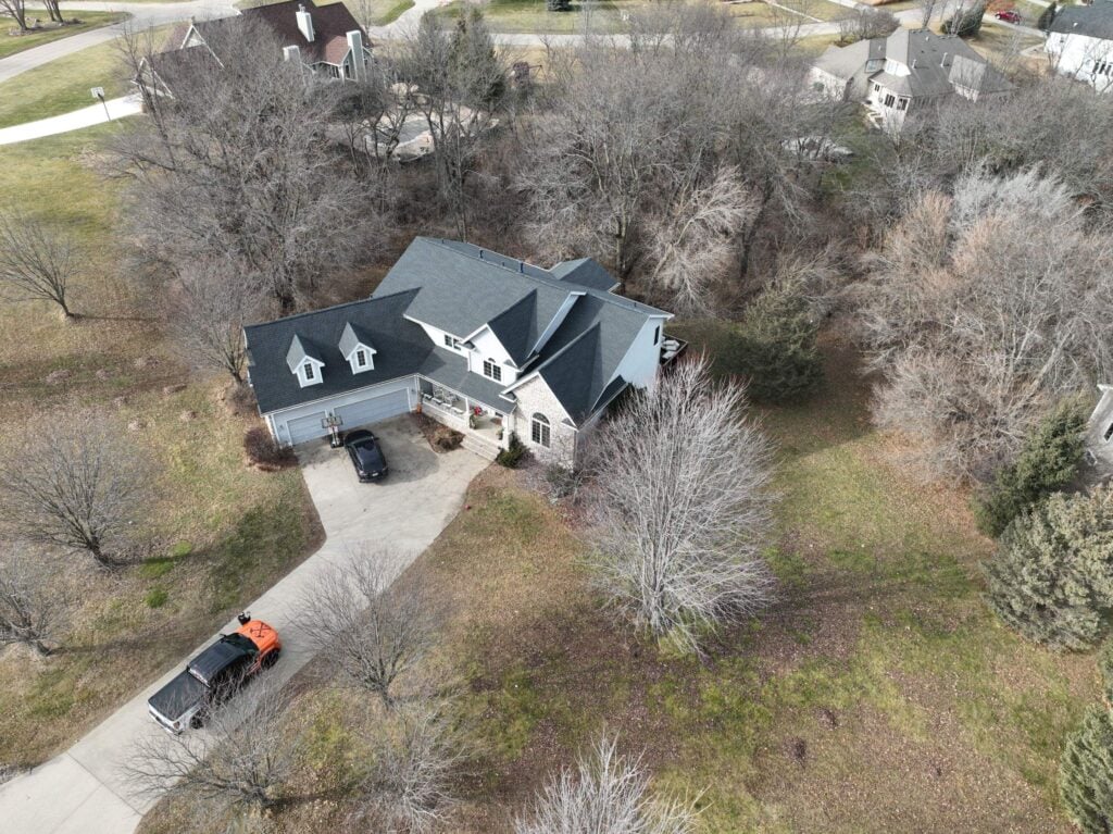 a house with a driveway and trees for a des moines roofing company
