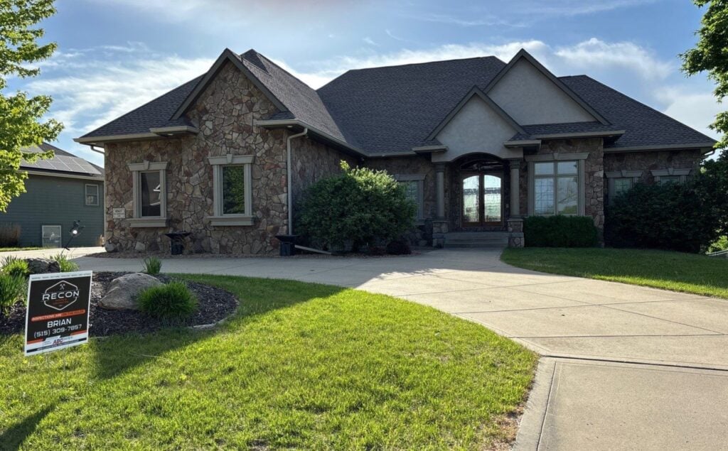 a house with a driveway and grass for a Des Moines roofing company