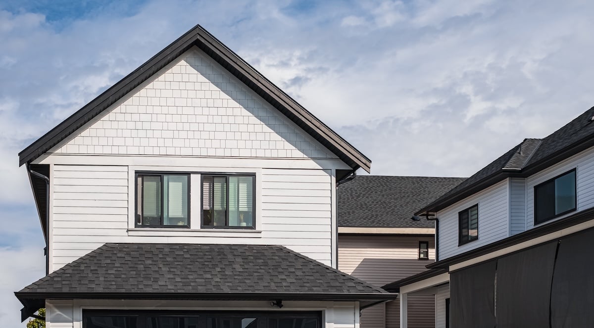 House with shingle roof against blue sky.