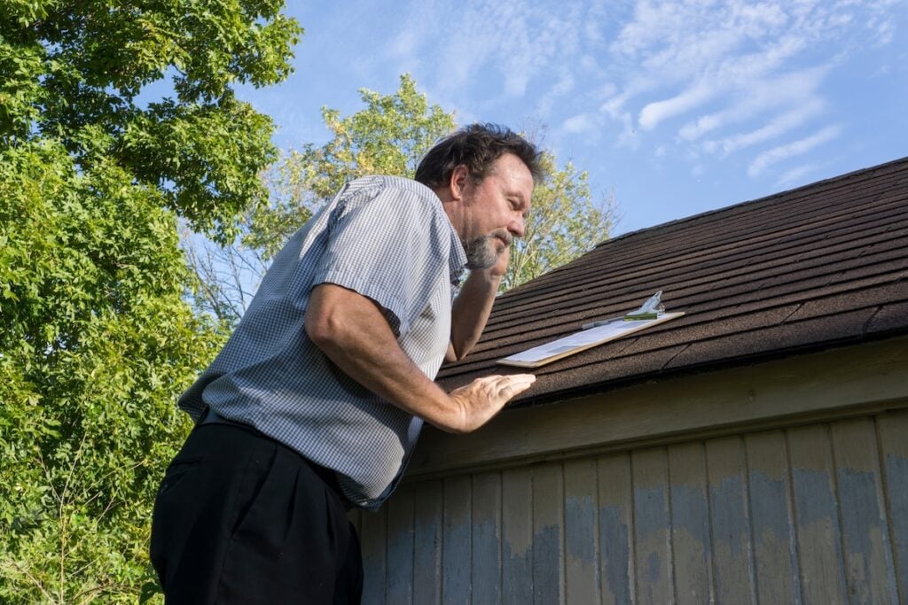 Insurance adjuster on cell phone while looking for hail damage.