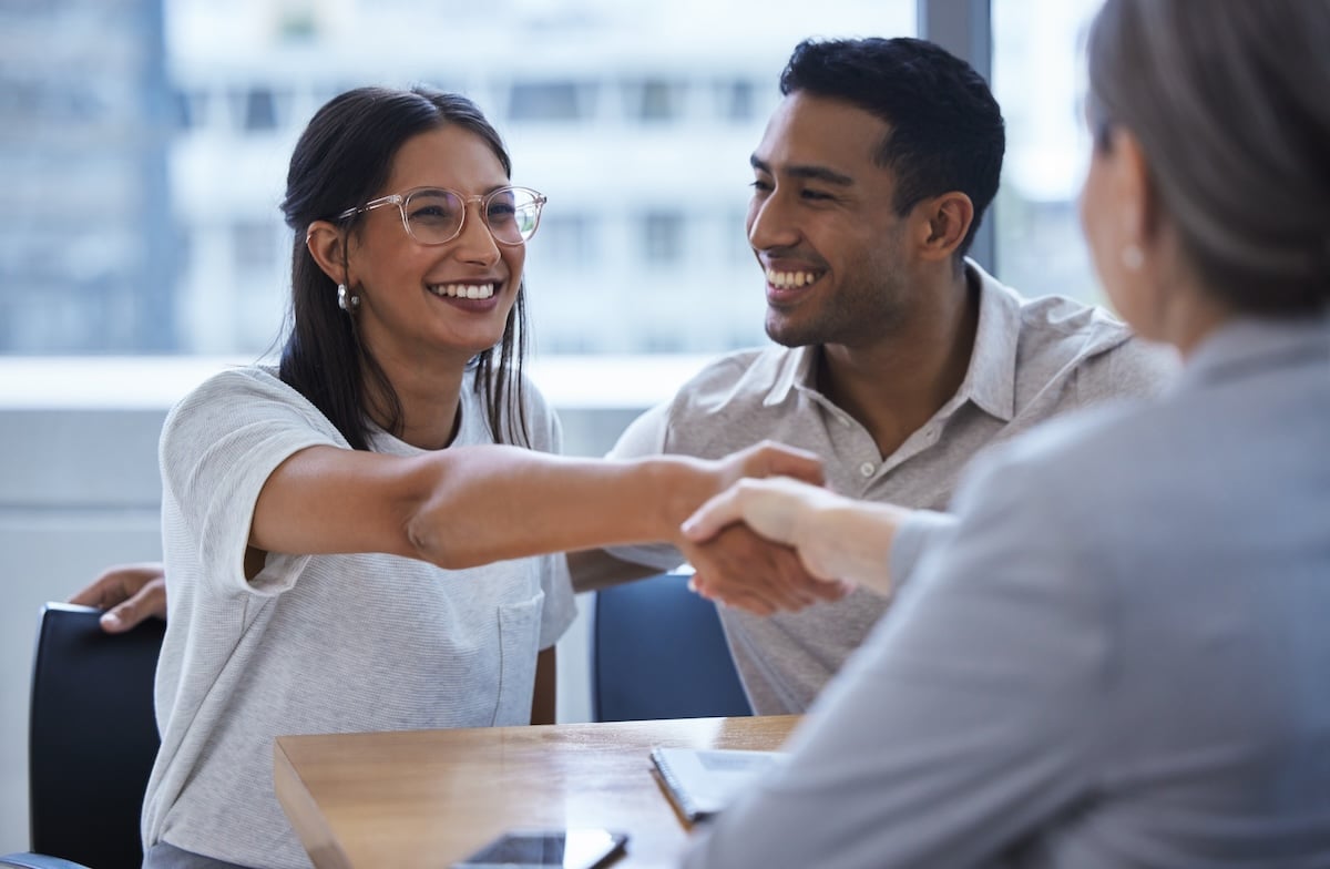 Shot of a young couple sharing a handshake with a consultant theyre meeting to discuss paperwork an office.